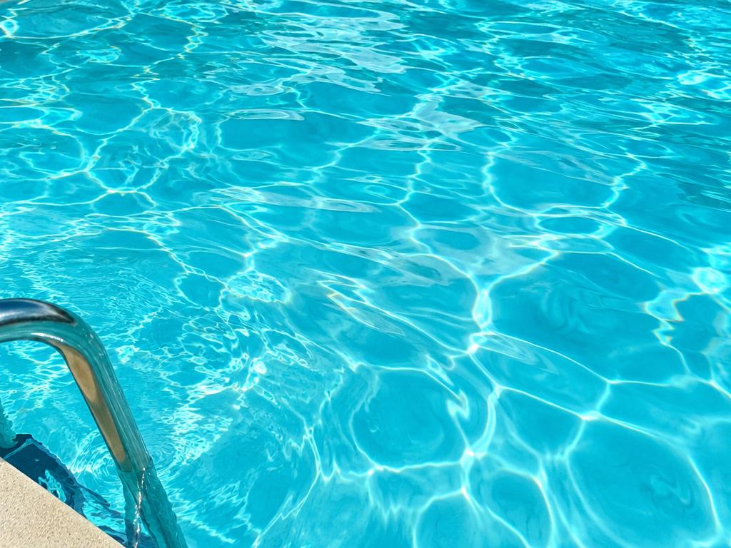 Clear pool water beside a landscaped poolside area